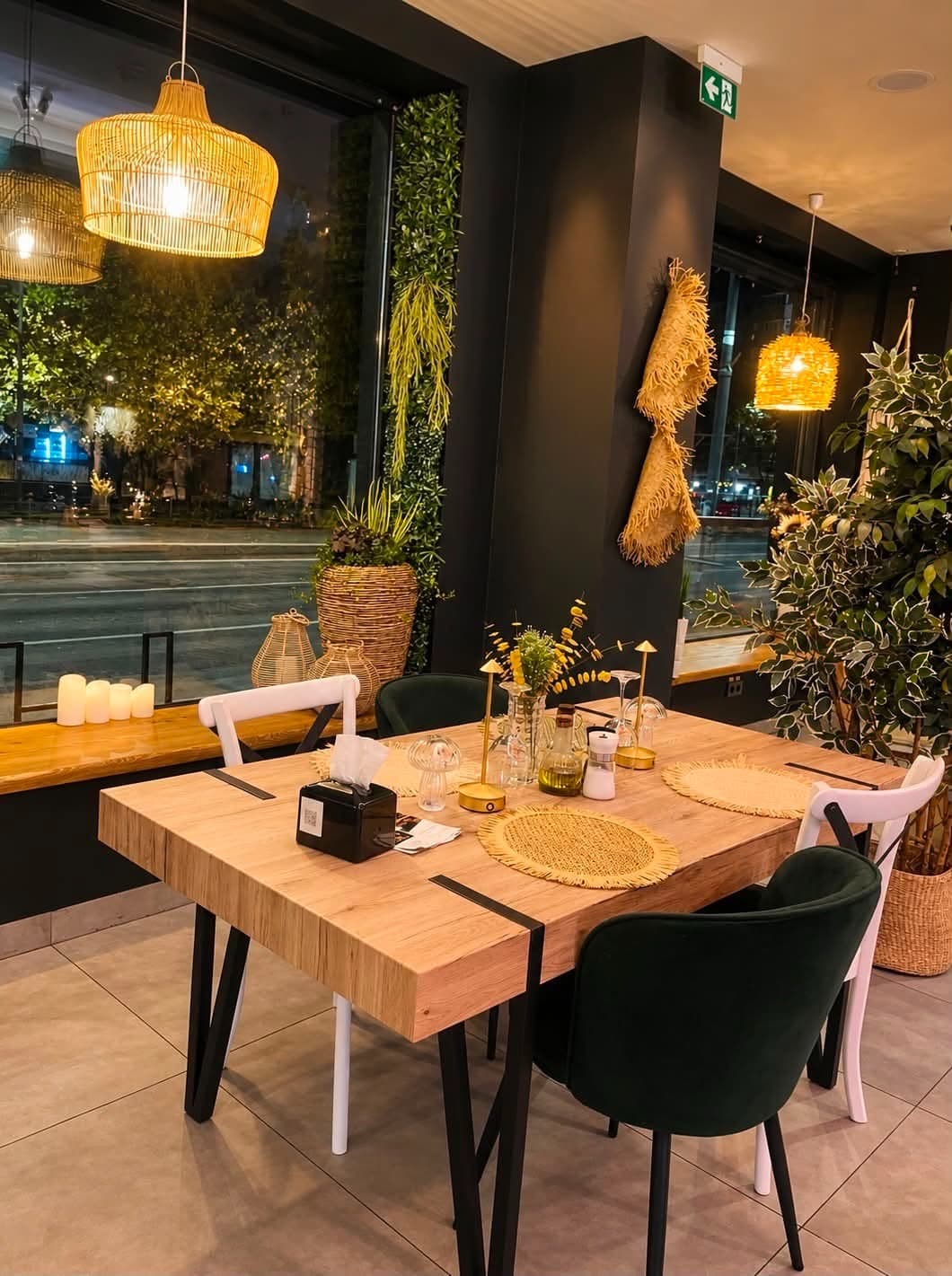 Masă pentru prieteni lângă ferestrele restaurantului, sub lămpi împletite